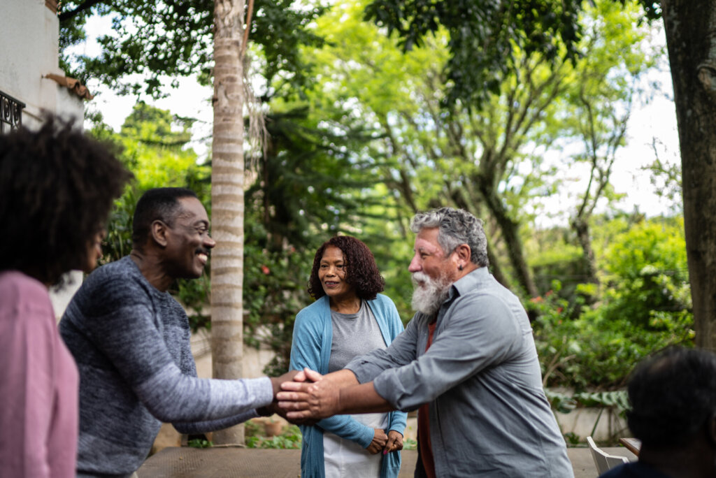 Three people gathered, two of them shaking hands.